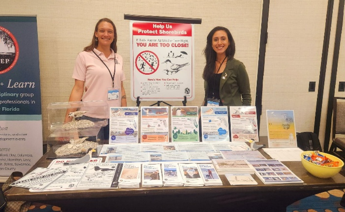Two FSA partners stand behind a table with fliers and other outreach material