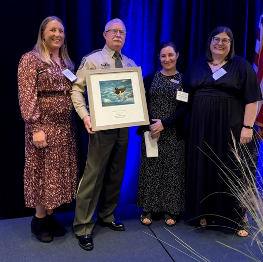 Officer Denis Palmer partner holding an award next to Audubon staff