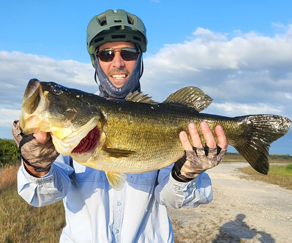 Angler with trophy Florida bass wearing bike helmet