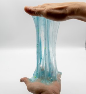 hands stretching blue glitter slime
