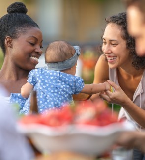 Two women interacting with baby at an outdoor gathering