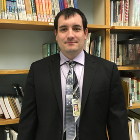 Bryant Capley standing in front of bookshelf
