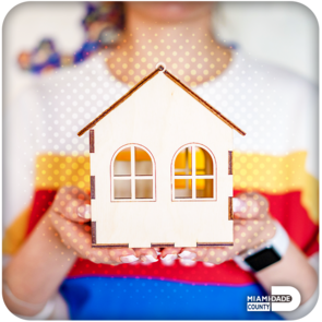 Woman holding a small, handcrafted wooden house in her hands