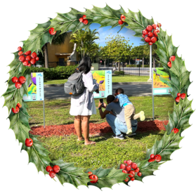 Family engaging with StoryWalk® panels, surrounded by greenery in a park setting
