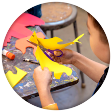 Kid cutting construction paper with scissors