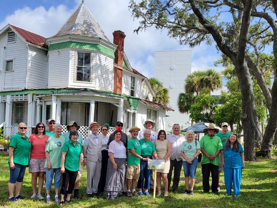 Group of volunteers at green gables in front of house receiving award
