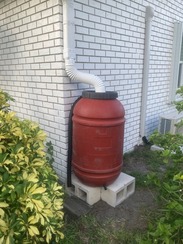 Rain barrel installed on the side of a house