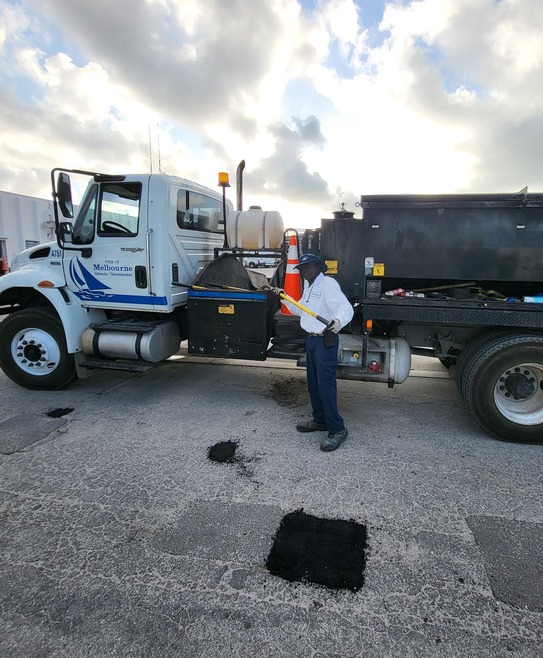 Silas, one of the streets crewmembers paving a pot hole