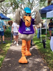 Pelly Can Mascot for Keep Brevard Beautiful walking on sidewalk with outreach tents on the side 