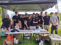 Group of people with black shirts representing Custom Tintz under a black tent