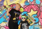 mother and a son smiling in front of colorful 80s backdrop