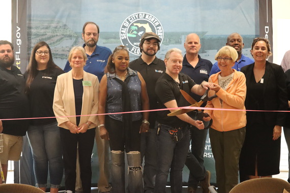 group of people cutting a ribbon with large scissors