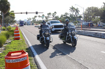 motorcycles drive next to construction cones