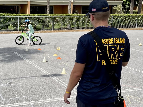 Treasure Island Bike Rodeo with firefighter watching a chiled in bike obstacle course