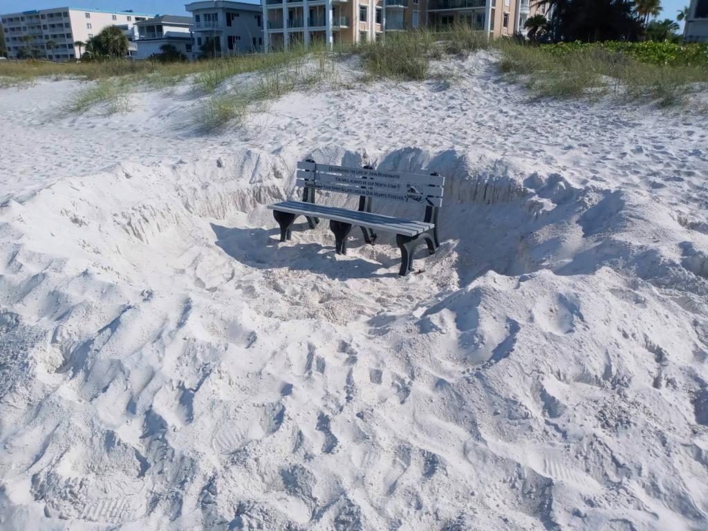 Park bench inside hole dug on beach