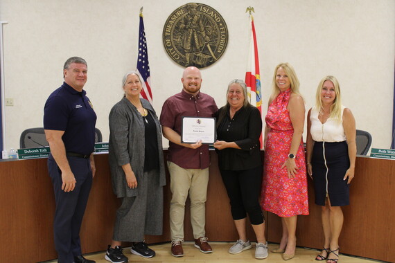 Paula Braun pictured with City Commissioners and her award for 10 years of service to the city