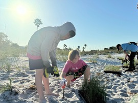 Two kids planting a sea oat on Treasure Island Beach
