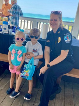 TIPD Detective poses for a picture with two kids at Coffee and Cupcakes with a cop