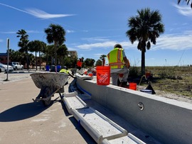 Crews working on repairing wall caps on Beach Trail wall