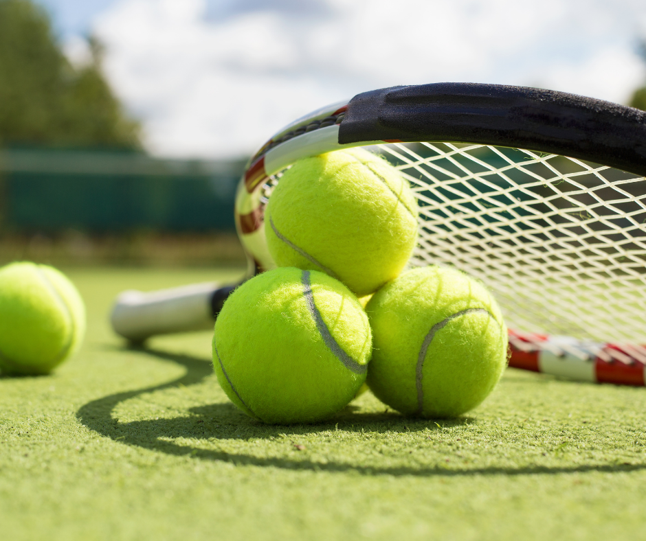 Tennis racket and tennis balls laying on a tennis court