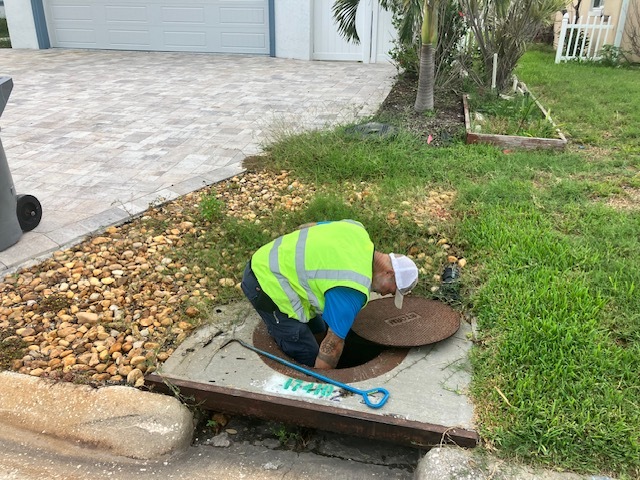 Public works crew member clearing a storm drain of debris