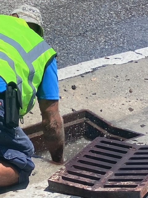 Public works crew member clearing a storm drain of debris