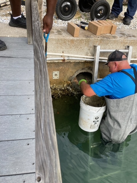 Public works crew member clearing a cathc basin of debris