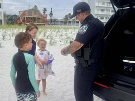 Treasure Island Police officer Quinn chatting with some kids on the beach