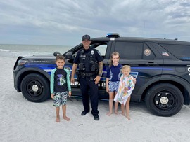 Treasure Island Police officer Quinn chatting poses for a pictures with some kids on the beach