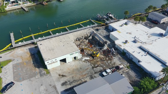 Aerial of public works garage being taken down by excavator