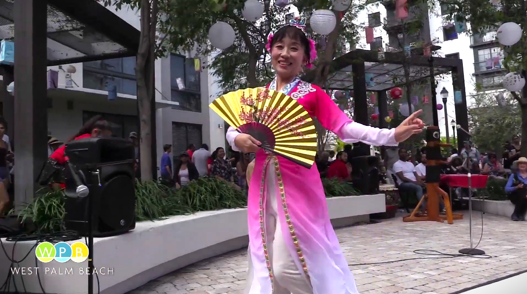 A woman smiles and holds a fan during the Lantern Festival - WPBTV YouTube Video Link 