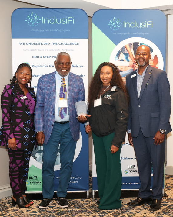 Group photo of 4 people and one person holding an award 