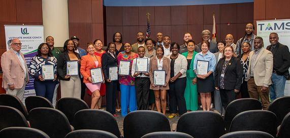 Group photo of several people and a young kind with an award in the middle; RFP Graduation Remarks