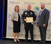 Officer HOLDS AWARD ON STAGE AND POSES FOR PHOTO WITH TWO OTHERS