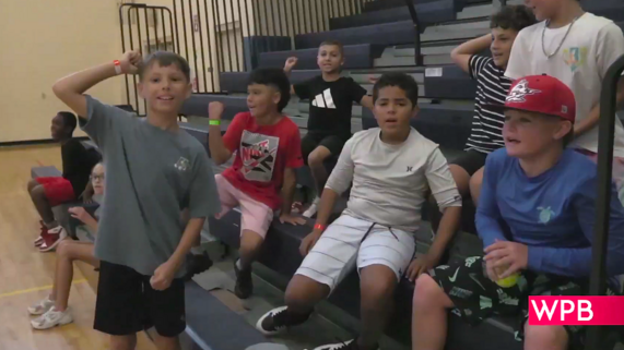 Kids smile for a photo on the bleachers in a gymnasium 