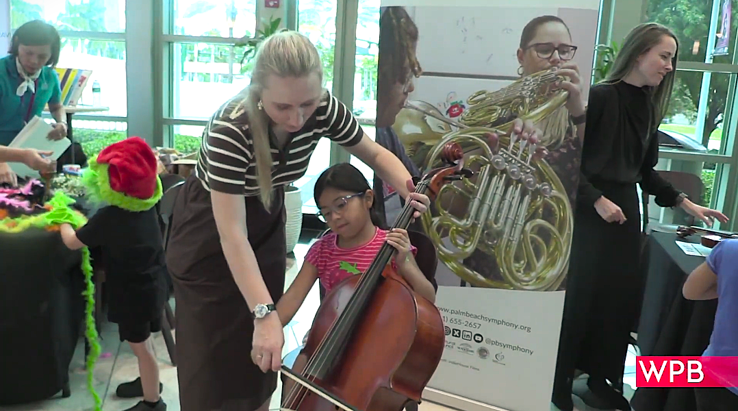 Little girl playing an instrument, being taught by an adult 