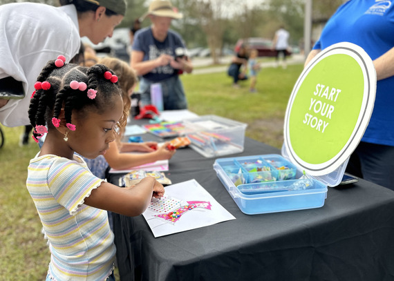 young girl engages in library's story activity at outdoor park