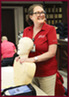 CPR instructor smiles at class while displaying CPR practice dummy