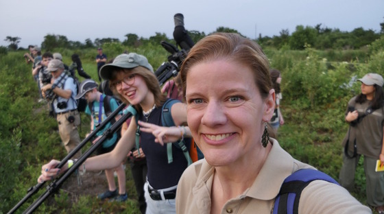Selfie with Linda May, a TALON leader, and teens -- one with a spotting scope over shoulder -- against green foliage
