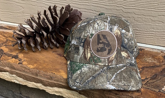 Camo cap beside a brown longleaf pine cone