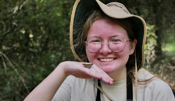 DNR staff in a tan hat with a small butterfly sitting on top of her hand