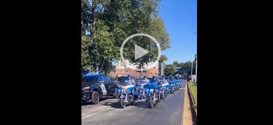 Video screen grab of law officers on motorcycles and in black SUVs in motorcade honoring DNR sargeant