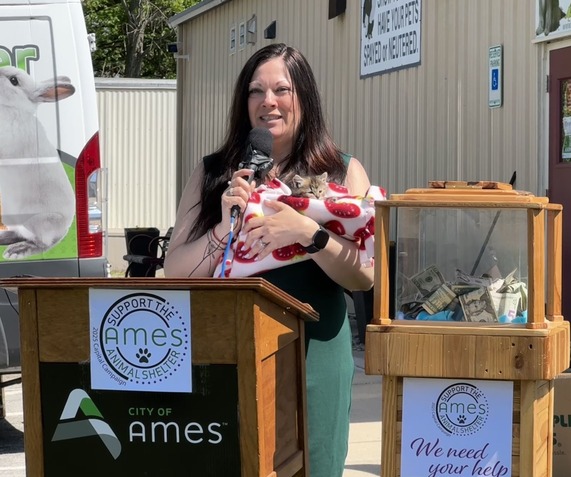Woman standing at a podium holding a kitten