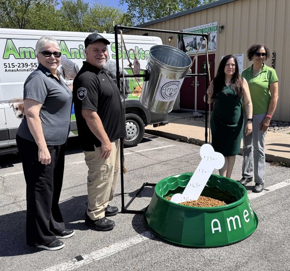 Four people standing next to a giant dog bowl filled with kibble