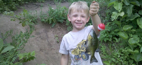 A young boy with his first fish caught - a bluegill.