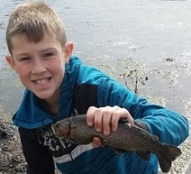 A boy with a trout he caught at a urban lake during a spring stocking event.