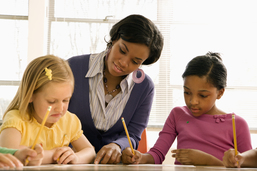 Teacher working with two young students.