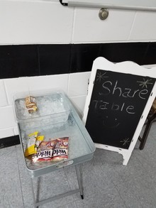 Photo of sharing table sign, and sharing table with food items placed on it.
