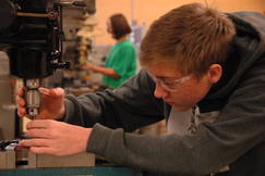 Student using a large, power drill in class.