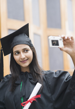 High school graduate holding diploma and taking a selfie